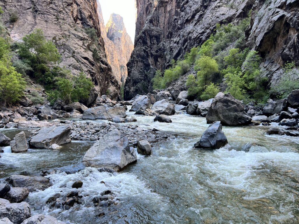 Hiker scrambling Class III boulders in Pinyon Draw, Black Canyon of the Gunnison North Rim.